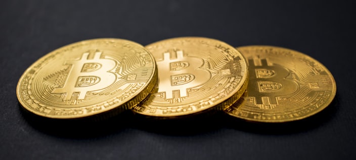 Three gold bitcoin coins on a black background